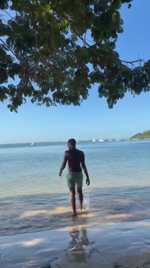 Kibwana walking into the sea at Tanga beach, with boats offshore.