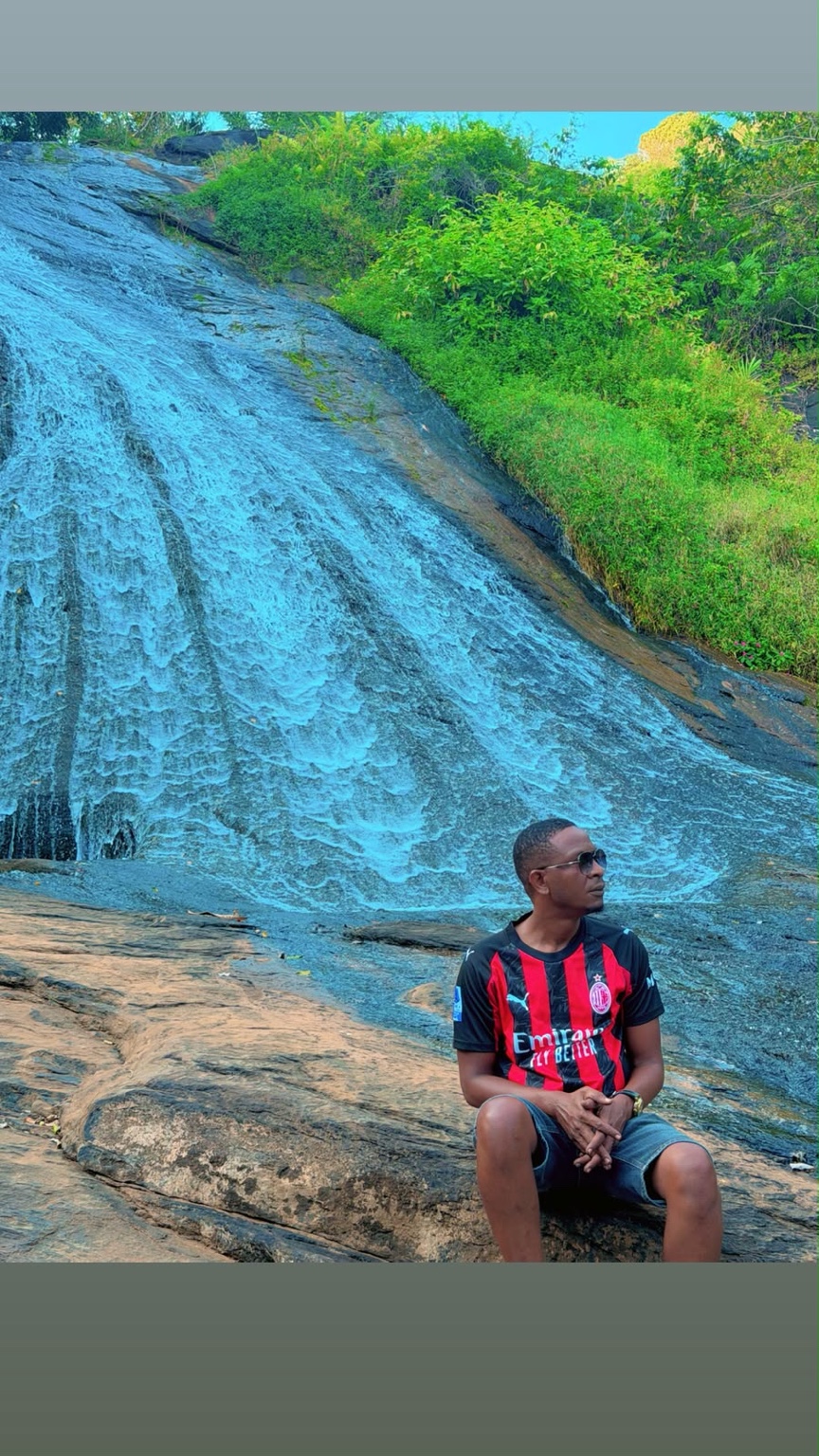 Kibwana seated beside a waterfall during his travels in the Tanga region.