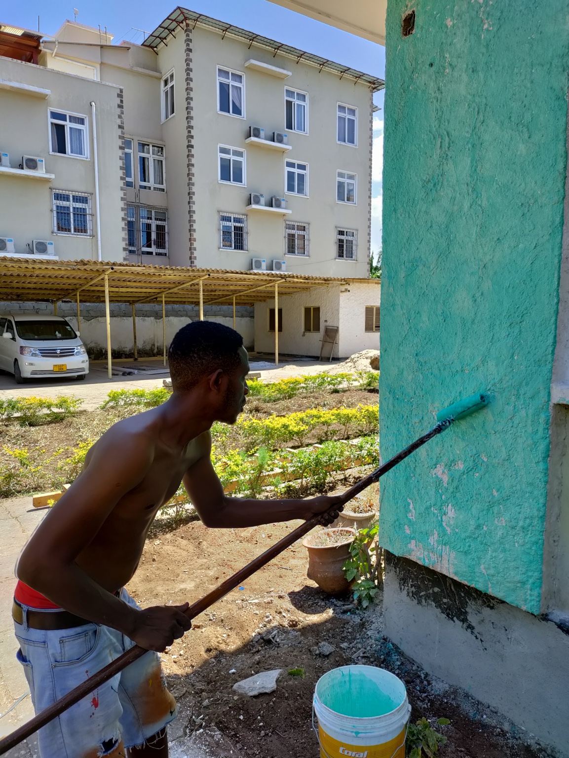 Kibwana painting an exterior wall during the early Gallivanters Hostel renovation