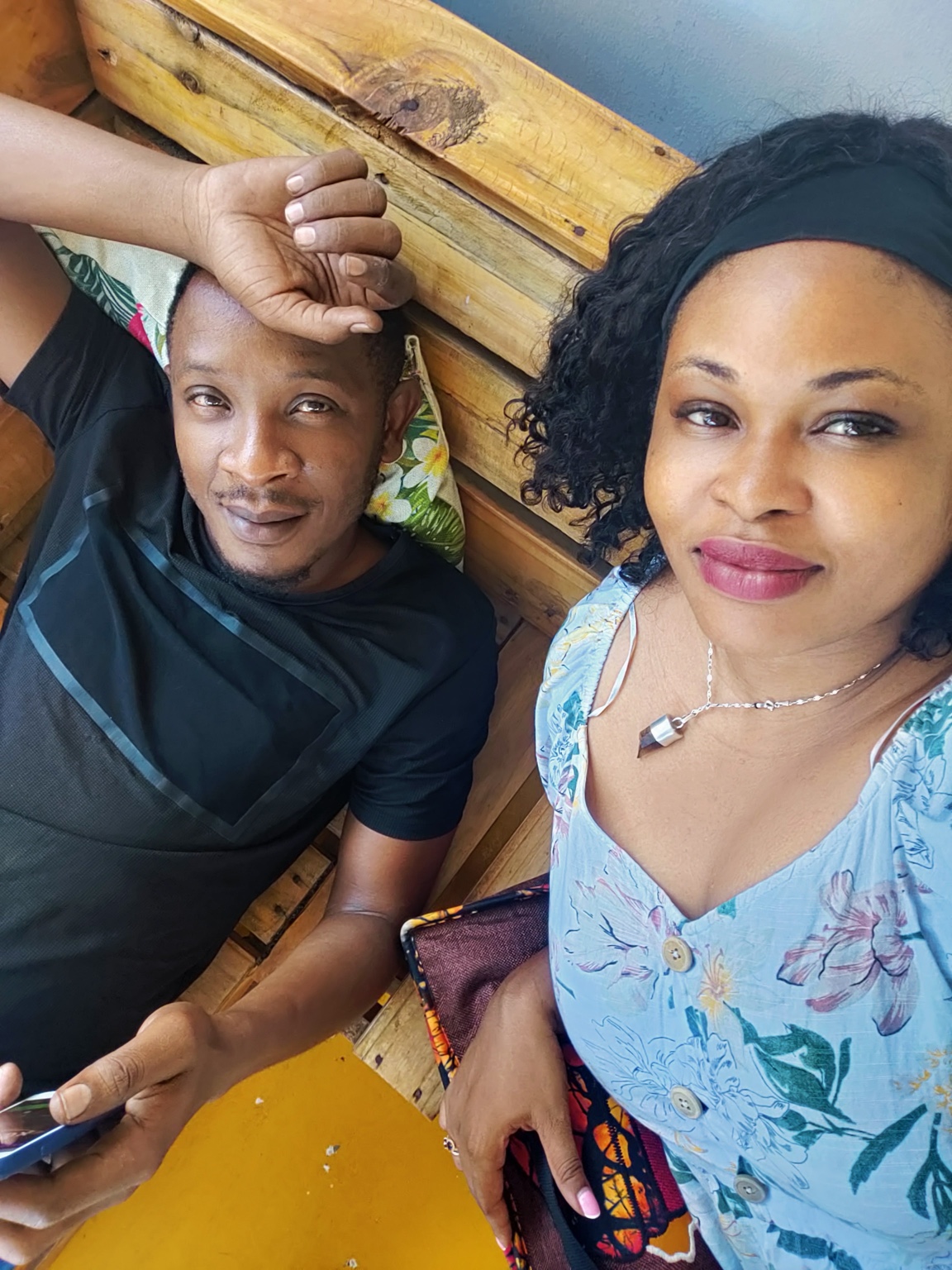 Tamara and Kibwana relaxing together on a wooden seat at Gallivanters Hostel.